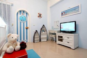 Una habitación infantil con televisor, un oso de peluche y una puerta a rayas.