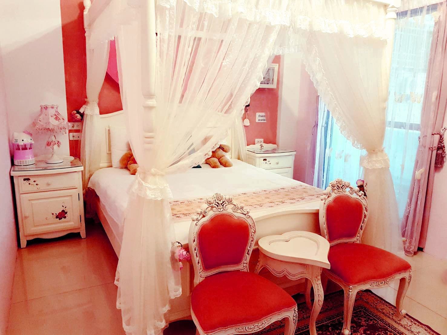 Un dormitorio con una cama con dosel, una mesita de noche, una silla y una pequeña mesa.