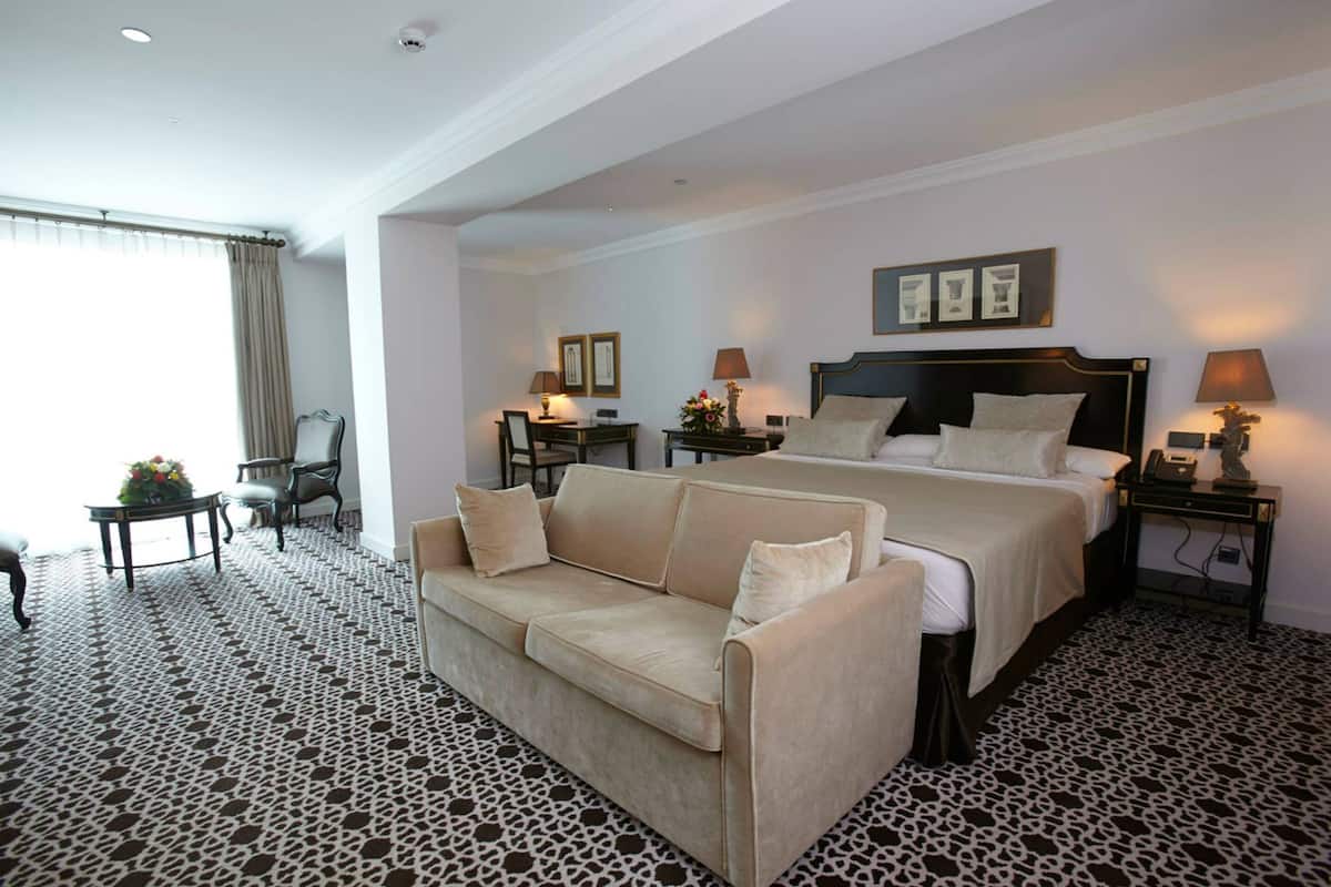 Una habitación de hotel con una cama grande, un sofá, un escritorio y una silla.