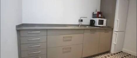 A small kitchen with a microwave, a refrigerator, and a sink.