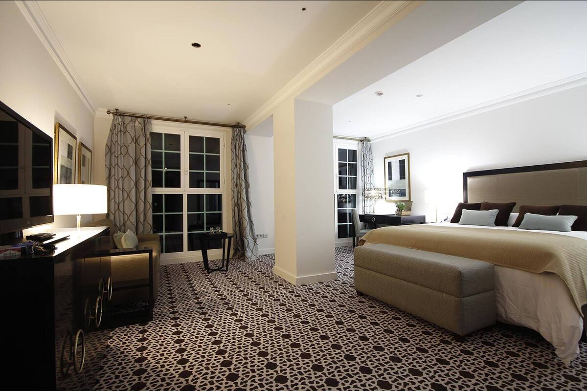 Una habitación de hotel con cama, mesita de noche, lámpara y escritorio con silla.