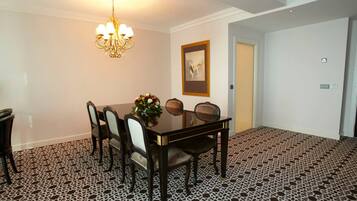 Een eetruimte met een tafel voor zes personen, een kroonluchter en een lijst aan de muur.