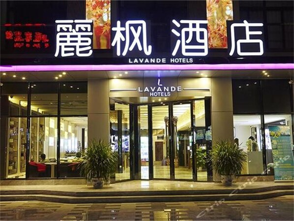 Exterior de Lavande Hotels con fachada moderna, amplios ventanales y plantas en macetas en la entrada.