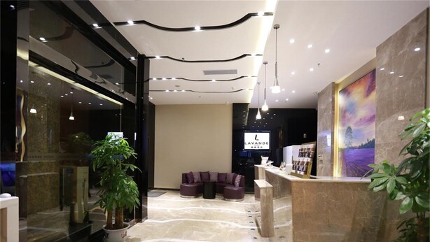 Un hall de hotel con mostrador de recepción, zona de estar y un ventanal grande.
