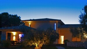 A two-story house with a visible moon in the sky, a well-lit entrance, and a stone pathway leading to the door. - Nature ET Design (Bonifacio)