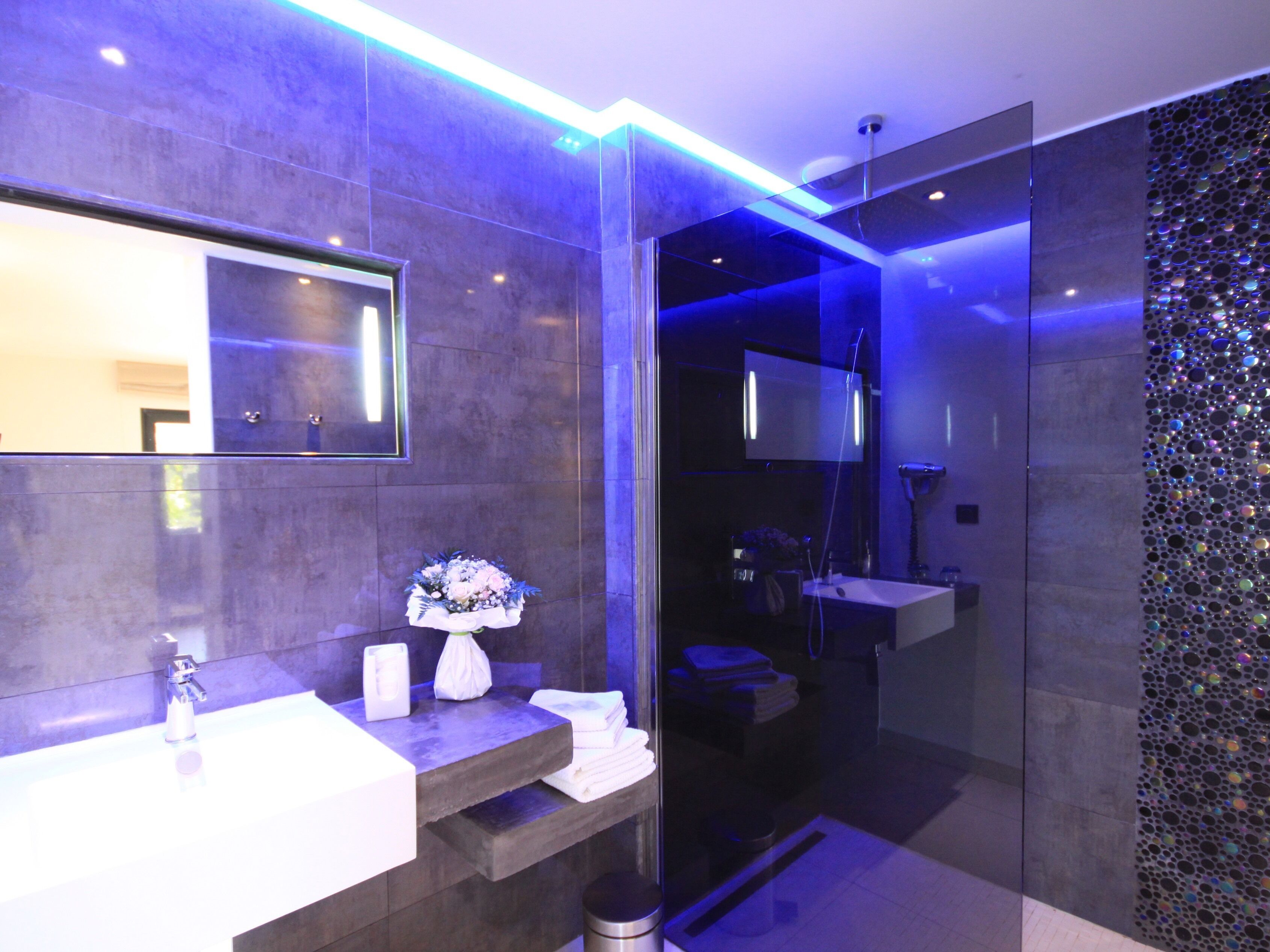 A modern bathroom with a vanity, mirror, and shower.