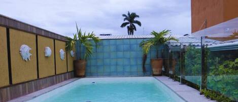 Una piscina al aire libre, sillones reclinables de piscina
