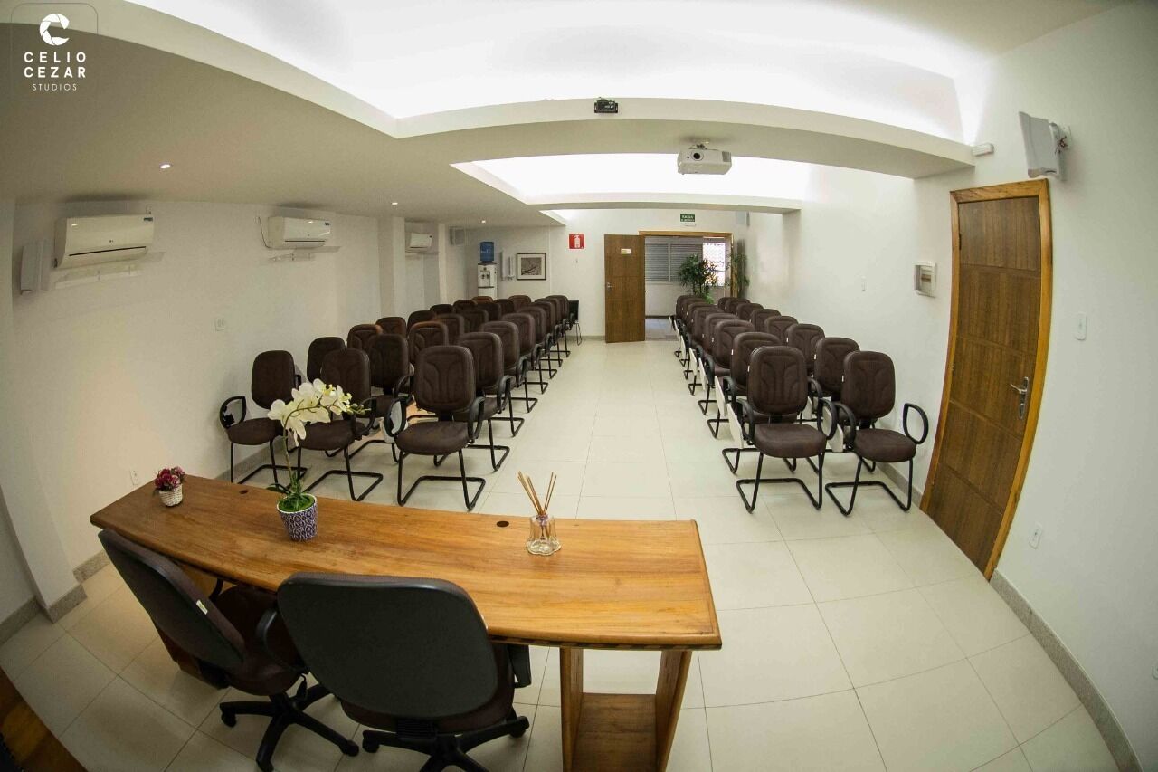 Un salón de conferencias con una larga mesa y sillas, unidades de aire acondicionado y una puerta de madera.