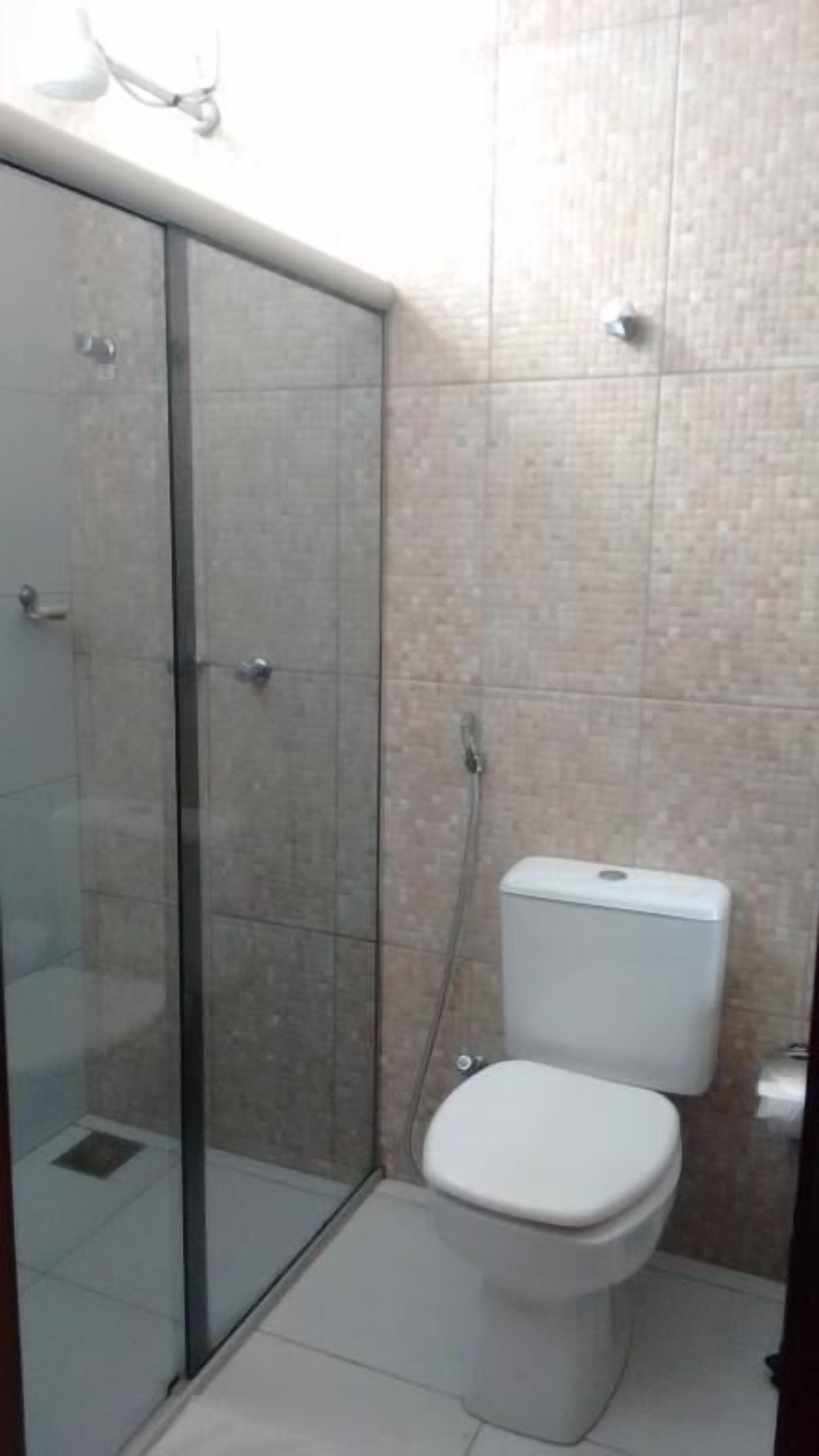 A bathroom with a glass-enclosed shower, a toilet, and tiled walls.
