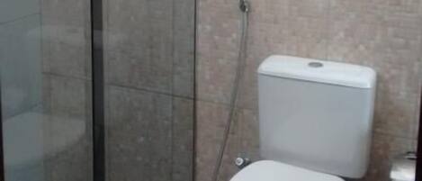 A bathroom with a glass-enclosed shower, a toilet, and tiled walls.