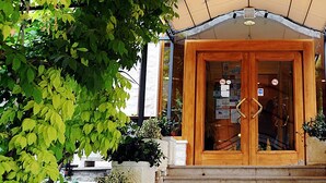 Un'ingresso in legno con porte in vetro, immerso nel verde.