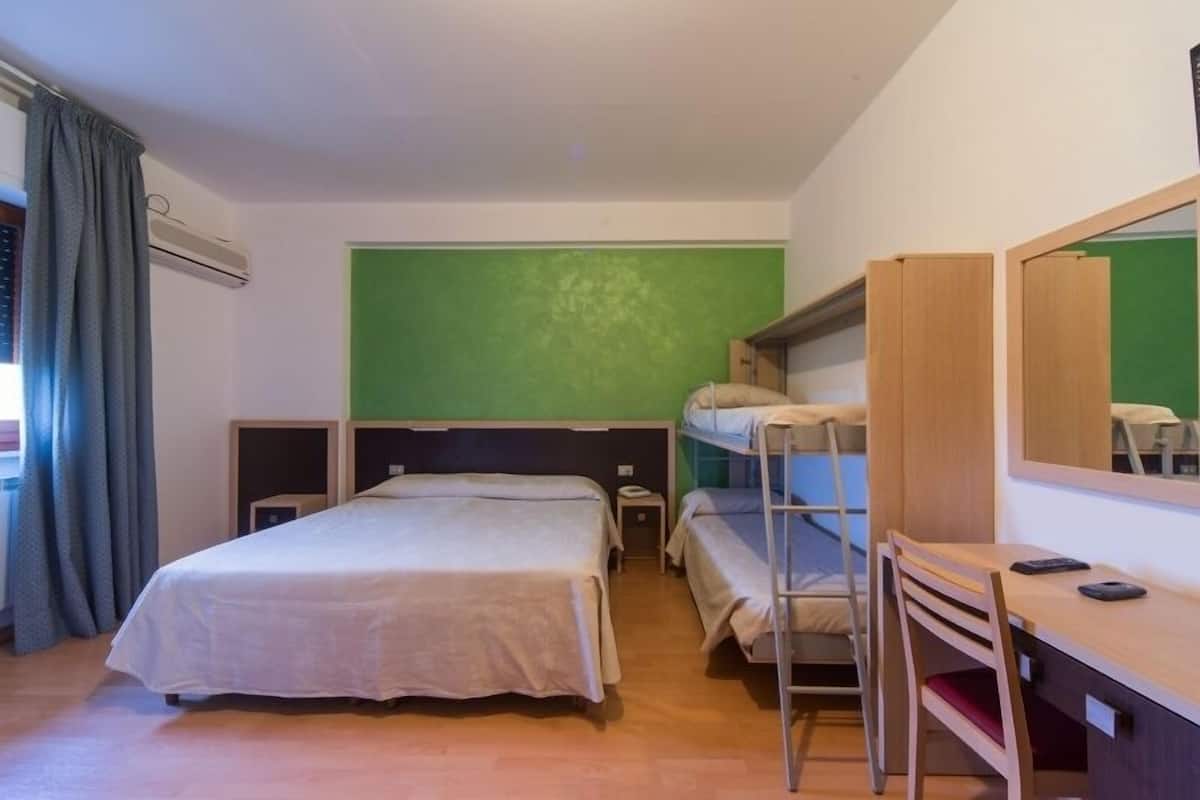 Una habitación con literas, un escritorio con silla, una mesita de noche pequeña y un espejo.