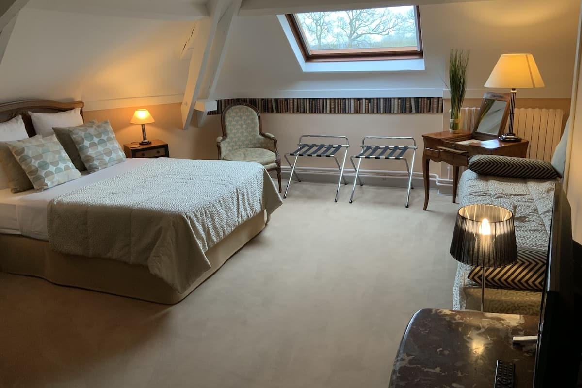 Une chambre à coucher avec un lit, deux chaises, un bureau, une lampe et une lucarne.