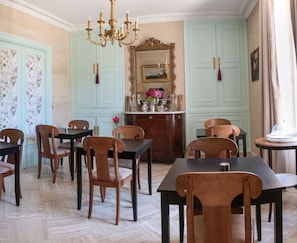 A dining room with a chandelier, floral wallpaper, and light blue doors. - Victoria Arromanches B&B (Tracy-sur-Mer)