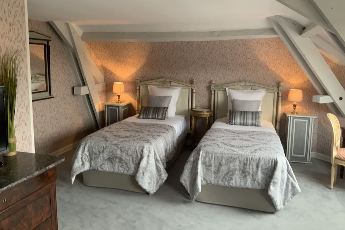 Une chambre avec deux lits, une commode et une chaise.