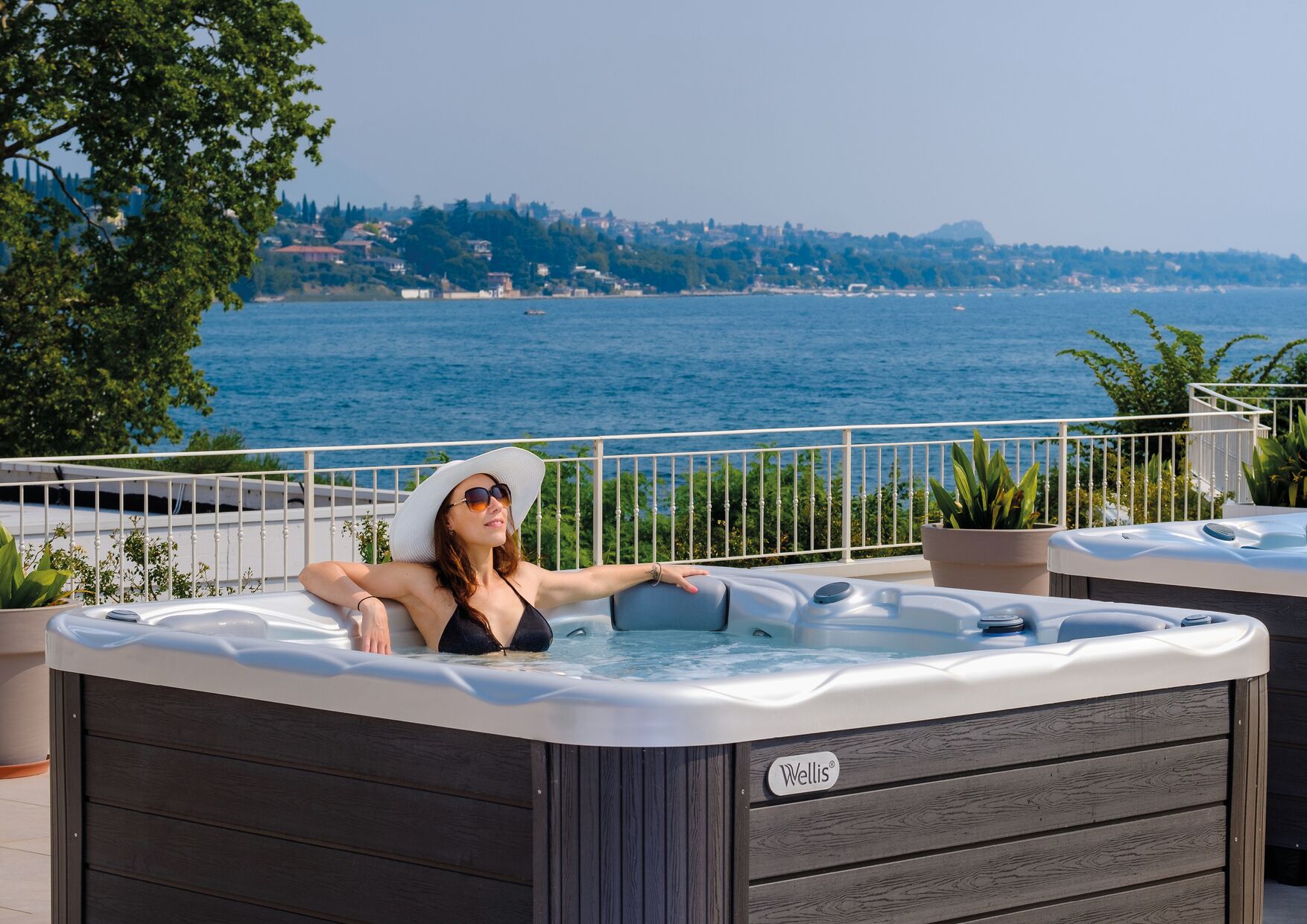 Eine Person entspannt sich in einer Badewanne mit Blick auf ein Gewässer und eine entfernte Küstenlinie.