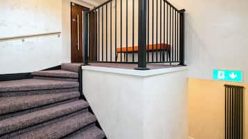 A staircase with a black railing and a wooden bench at the top.