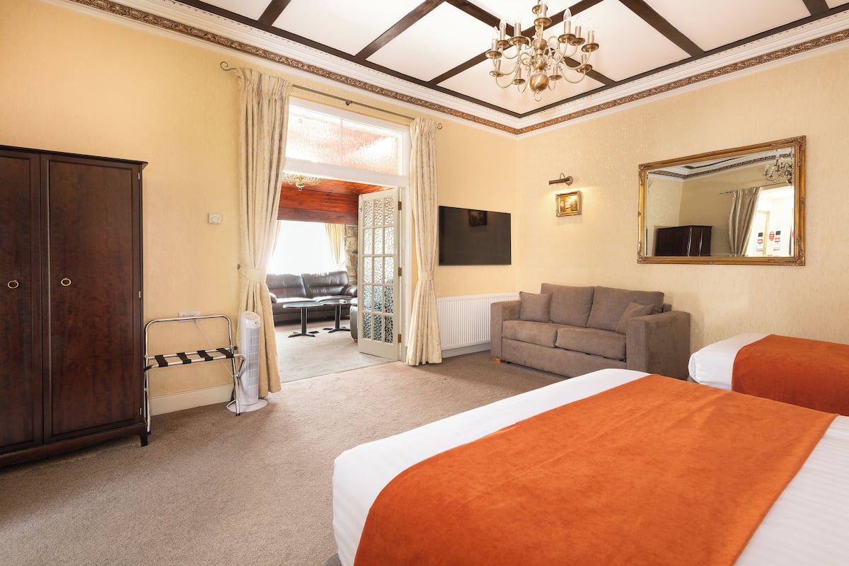 Ein Hotelzimmer mit zwei Betten, einer Couch, einem Fernseher und einem großen Spiegel.