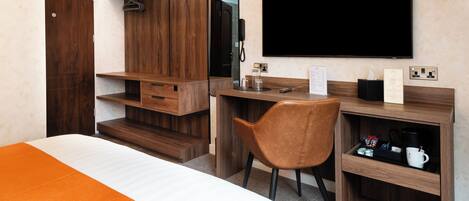 A hotel room with a bed, a desk, a chair, a TV, and a wardrobe.