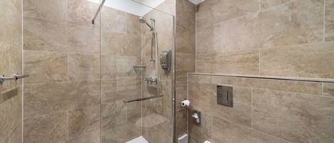 Une salle de bain moderne avec une douche à parois de verre, des toilettes blanches et des carreaux de couleur beige.