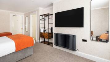 Habitación de hotel con cama, televisión, radiador y espejo.