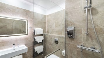 A modern bathroom with a glass-enclosed shower, a white sink, and a mirror.