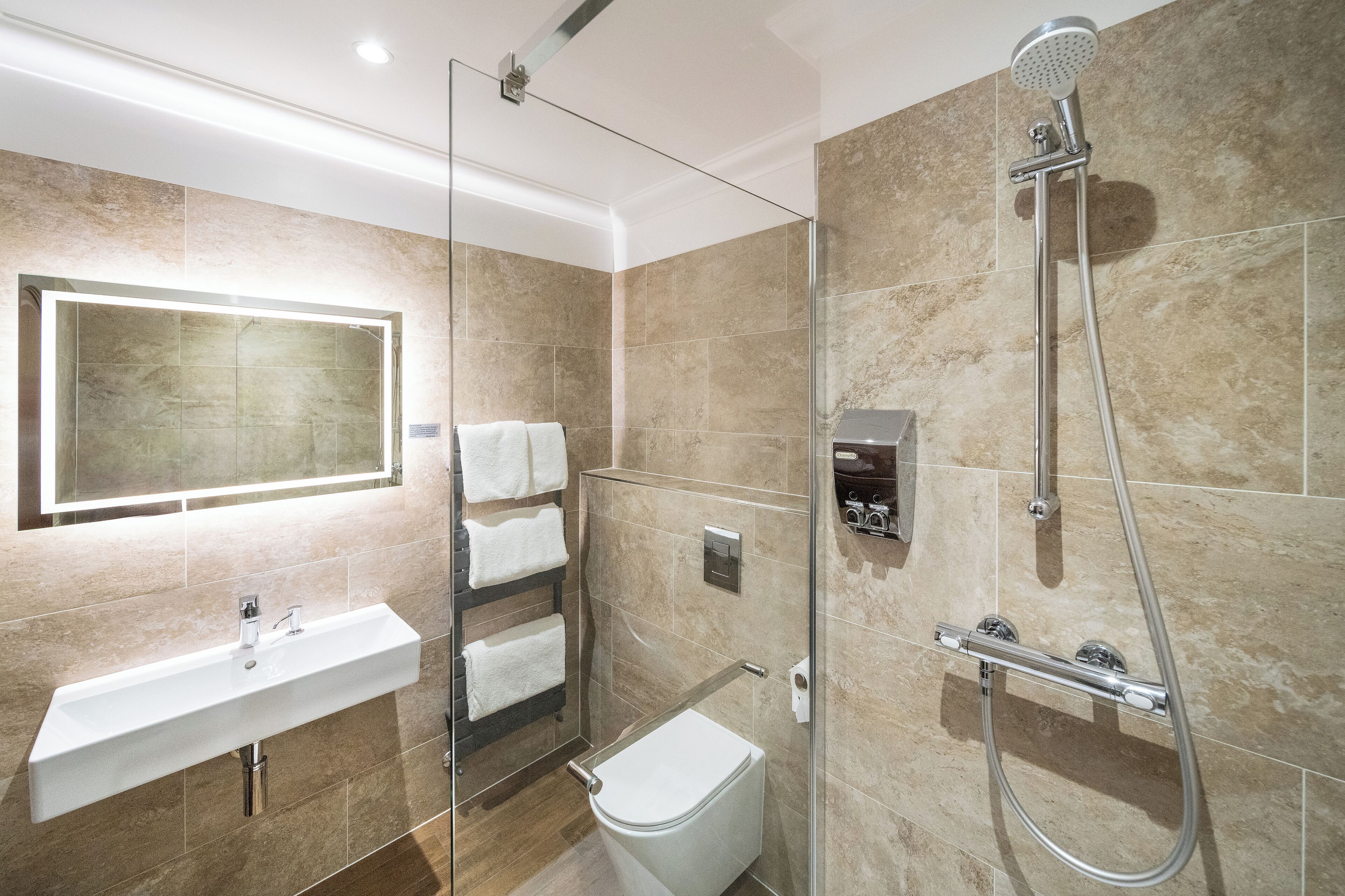 A modern bathroom with a glass-enclosed shower, a built-in sink, and a toilet.