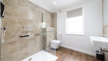 Een moderne badkamer met een glazen douchecabine, een wit toilet en een wastafel.