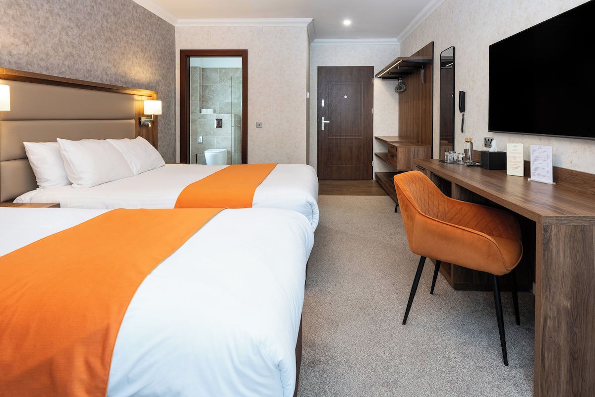 Ein Hotelzimmer mit zwei Betten, einem Schreibtisch und einem Stuhl.