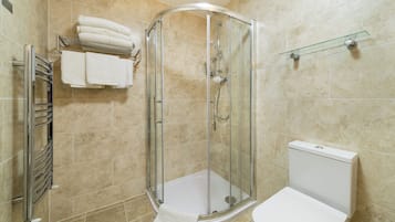 Een moderne badkamer met een douche met glazen wand, een toilet en een handdoekrek met opgevouwen handdoeken.
