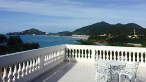 A balcony with a white balustrade, a table with chairs, and a view of the sea and mountains. - Recanto do Teimoso Ubatuba (Ubatuba)