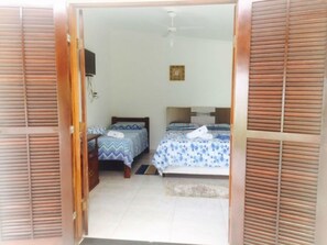 Quarto com duas camas, um ventilador de teto e um tapete pequeno.