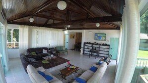A spacious living area with a high ceiling, a sofa set, a coffee table, and a bookshelf. - Recanto do Teimoso Ubatuba (Ubatuba)