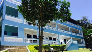 A blue multi-story building with balconies, a staircase, and a statue of a horse. - Recanto do Teimoso Ubatuba (Ubatuba)