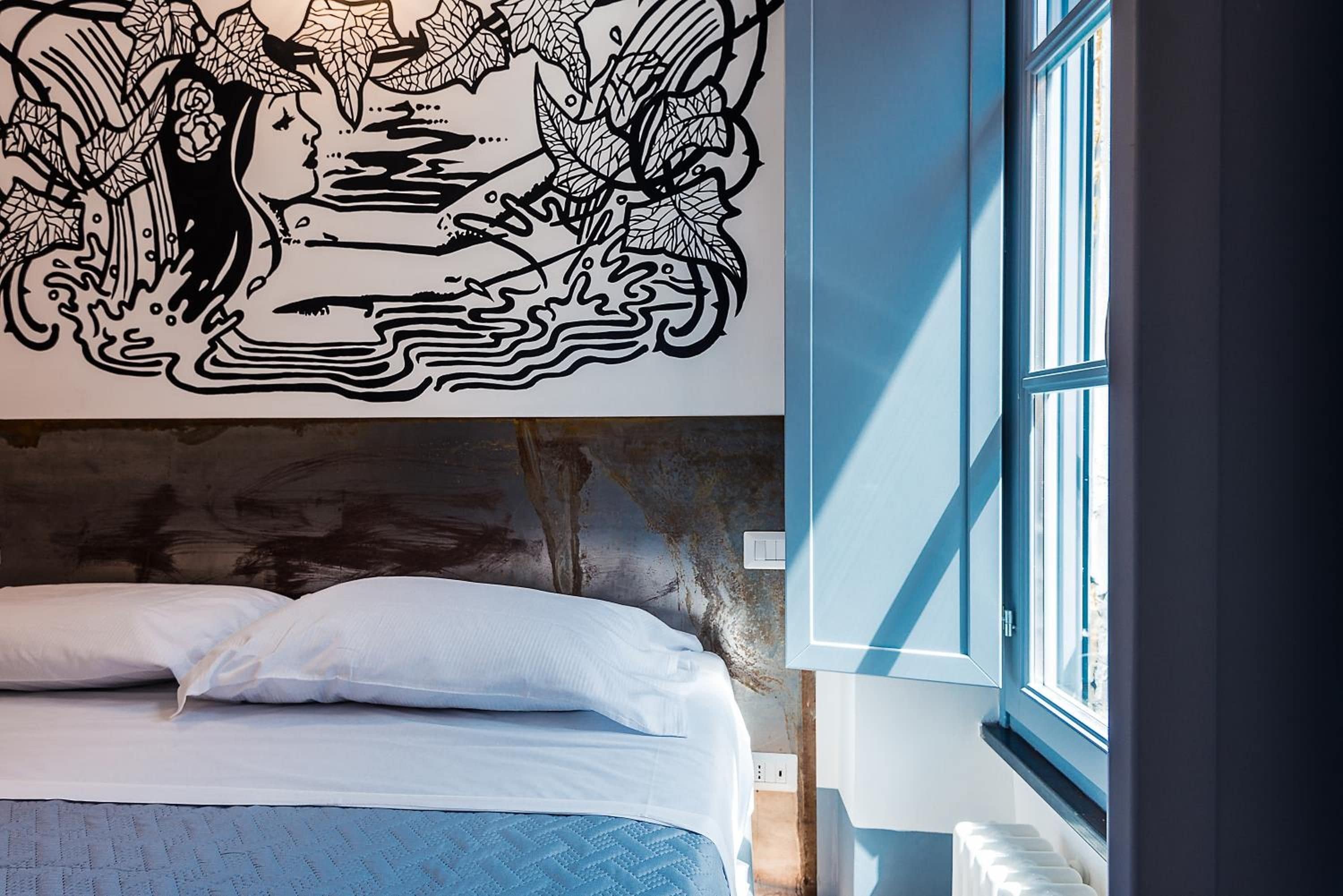 A bedroom with a bed, a wall mural, and a window.