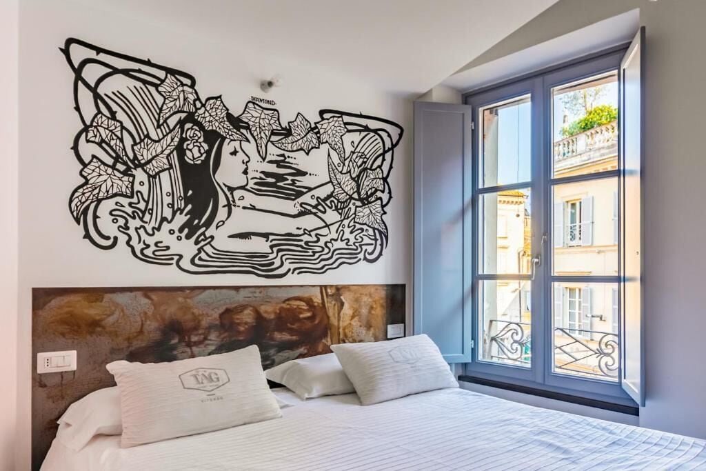A bedroom with a large bed, a headboard with a textured design, and a wall-mounted artwork.