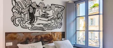 A bedroom with a large bed, a headboard with a textured design, and a wall-mounted artwork.