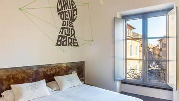 Ein Schlafzimmer mit einem Bett, einem Wandbild und einem Fenster mit Blick auf Gebäude.