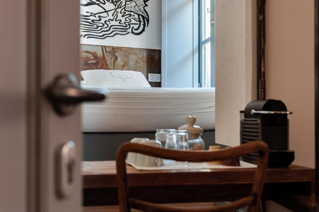 Una habitación con una cama, una ventana, una mesa con una silla y un diseño decorativo en la pared.