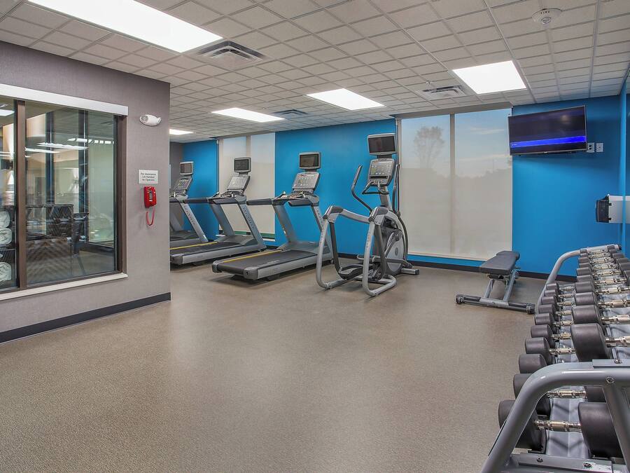 A gym with treadmills, elliptical machines, and weight benches.