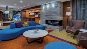 A modern living room with a blue sectional sofa, a round coffee table, and a fireplace. - Fairfield Inn & Suites by Marriott Nashville Hendersonville (Hendersonville)
