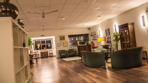 A spacious room with a wooden floor, green chairs, a desk, and a ceiling fan. - Hotel Fljotshlid (Rangárþing eystra)