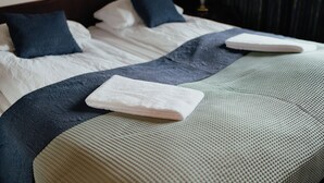 A neatly made bed with white linens, a blue throw blanket, and two folded white towels. - Hotel Fljotshlid (Rangárþing eystra)