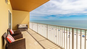 Een balkon met rieten meubels en uitzicht op het strand.