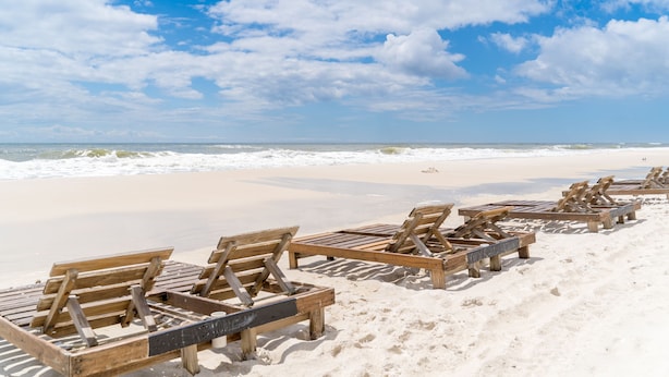 Een strand met rijen houten ligbedden.
