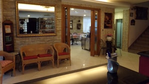A spacious living area with wicker furniture, a large mirror, and a chandelier. - Hotel Manù (Rimini)