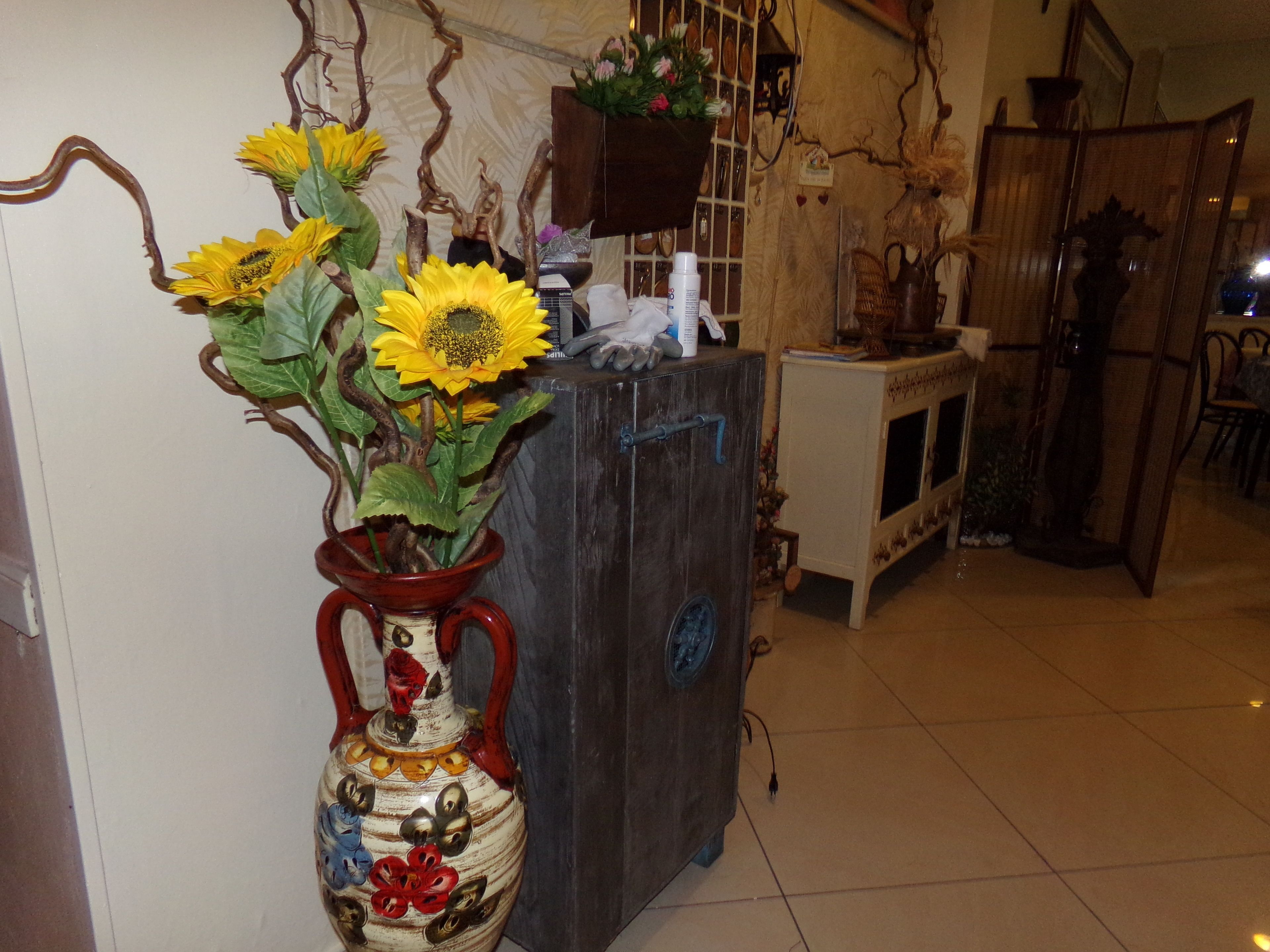 Een kamer met een houten kast, een vaas met zonnebloemen en een spiegel aan de muur.