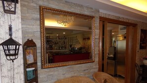A room with wicker chairs, a large mirror, and a bar area visible through the mirror. - Hotel Manù (Rimini)