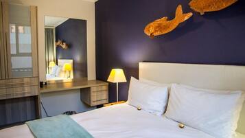 Een hotelkamer met een bed, een bureau, een spiegel en een visbeeld aan de muur.