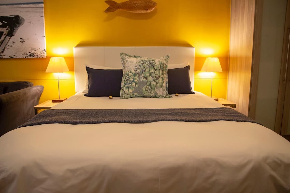 A hotel room with a large bed, two bedside lamps, a headboard, and a fish decoration on the wall.